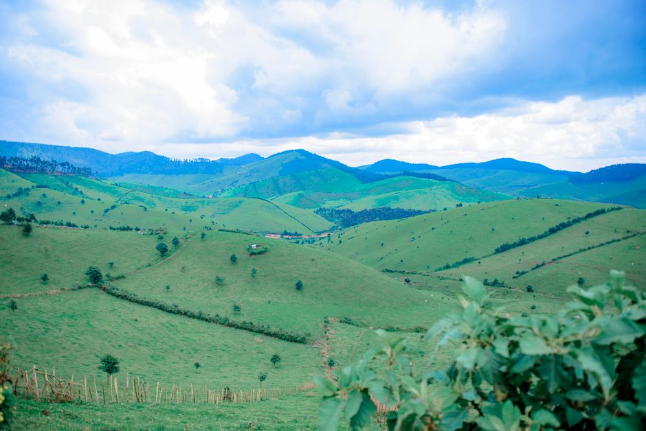 Explore the serene green hills under a dramatic sky, captured in a stunning aerial landscape view.