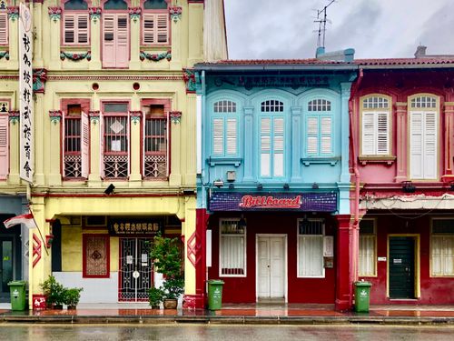 Free Colorful colonial shophouses on a wet street, capturing urban charm and architecture. Stock Photo