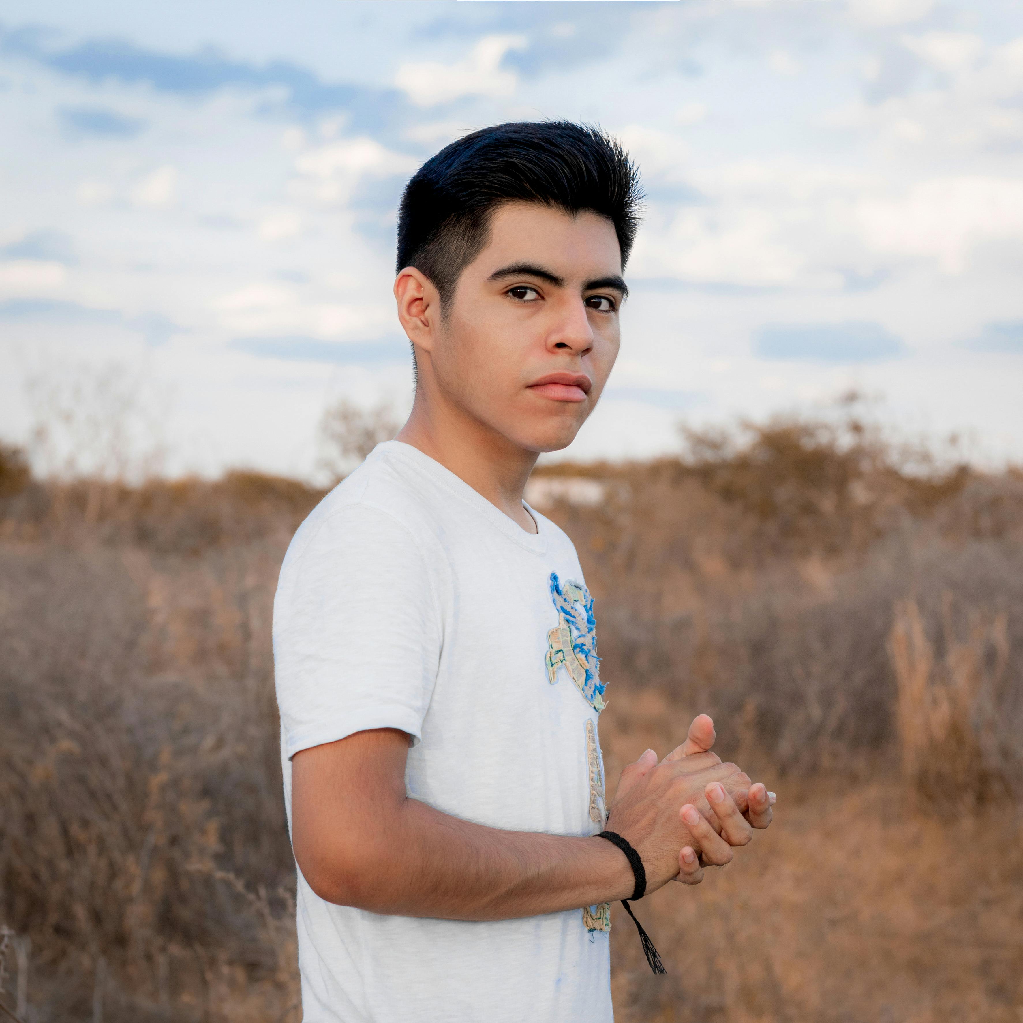 Portrait of a young man standing outdoors in a natural, dry landscape.