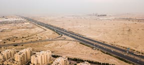 无人机拍摄了下方有建筑物的、穿过迪拜沙漠景观的高速公路