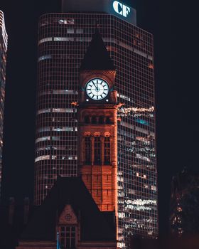 Captivating view of Toronto's Old City Hall clock tower illuminated at night with a modern building backdrop.