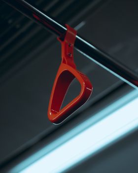 A close-up view of a red handle inside a public transportation vehicle, emphasizing its sleek design.