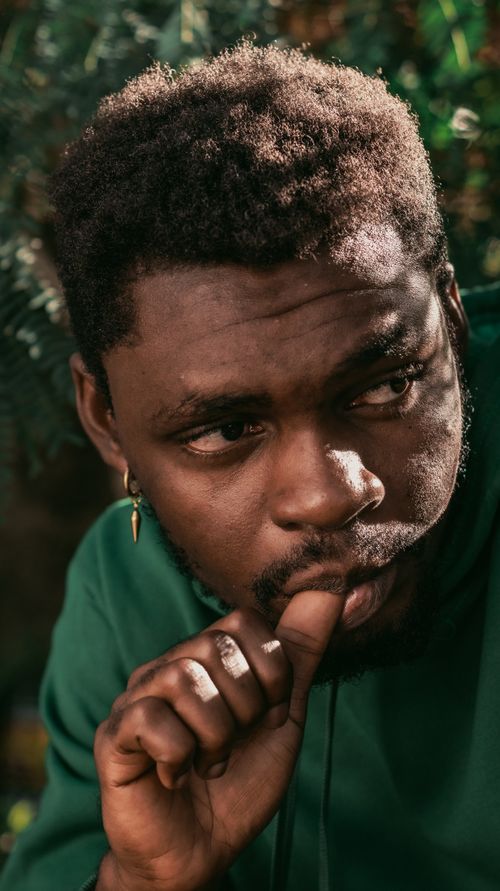 Free Close-up portrait of a thoughtful young man with natural surroundings. Stock Photo