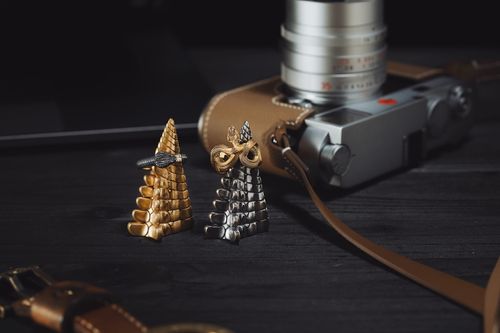 Free Detailed shot of intricate silver and gold snake rings next to a vintage camera on a dark surface. Stock Photo