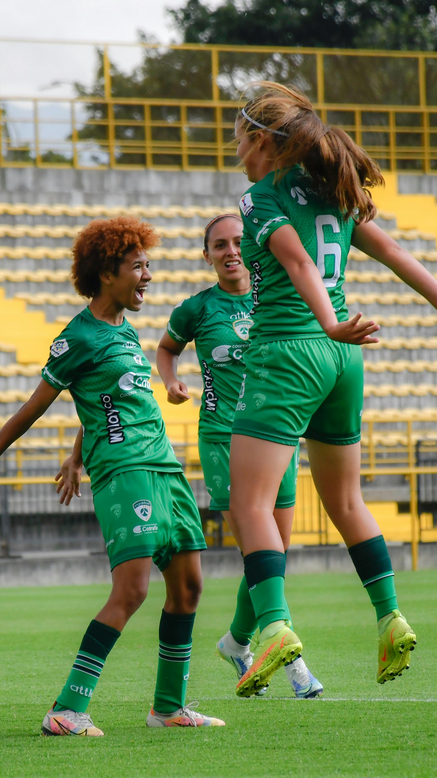 A joyful moment as female football players celebrate a goal on the field.