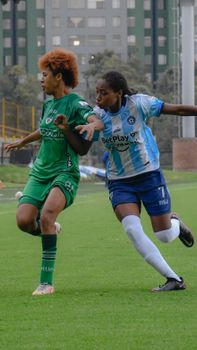 A dynamic capture of two women soccer players competing on the field during a match.