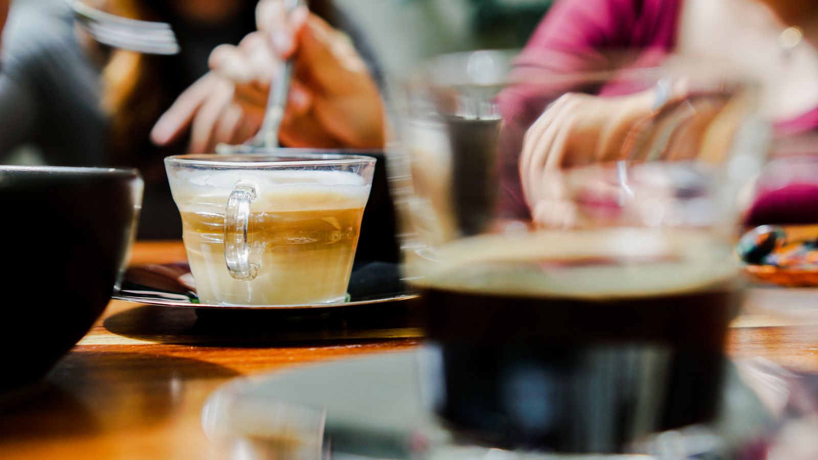 Coffee cups on a table with people seated in the background