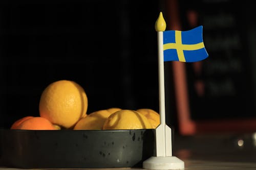 Close-up of a Small, Plastic Flag of Sweden and a Tray with Lemons 