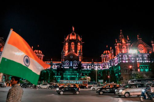 Free Night view of Chhatrapati Shivaji Terminus in Mumbai with vibrant lights and Indian flag. Stock Photo
