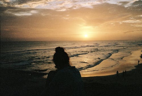 Free Silhouette of a Woman on the Beach at Sunset  Stock Photo