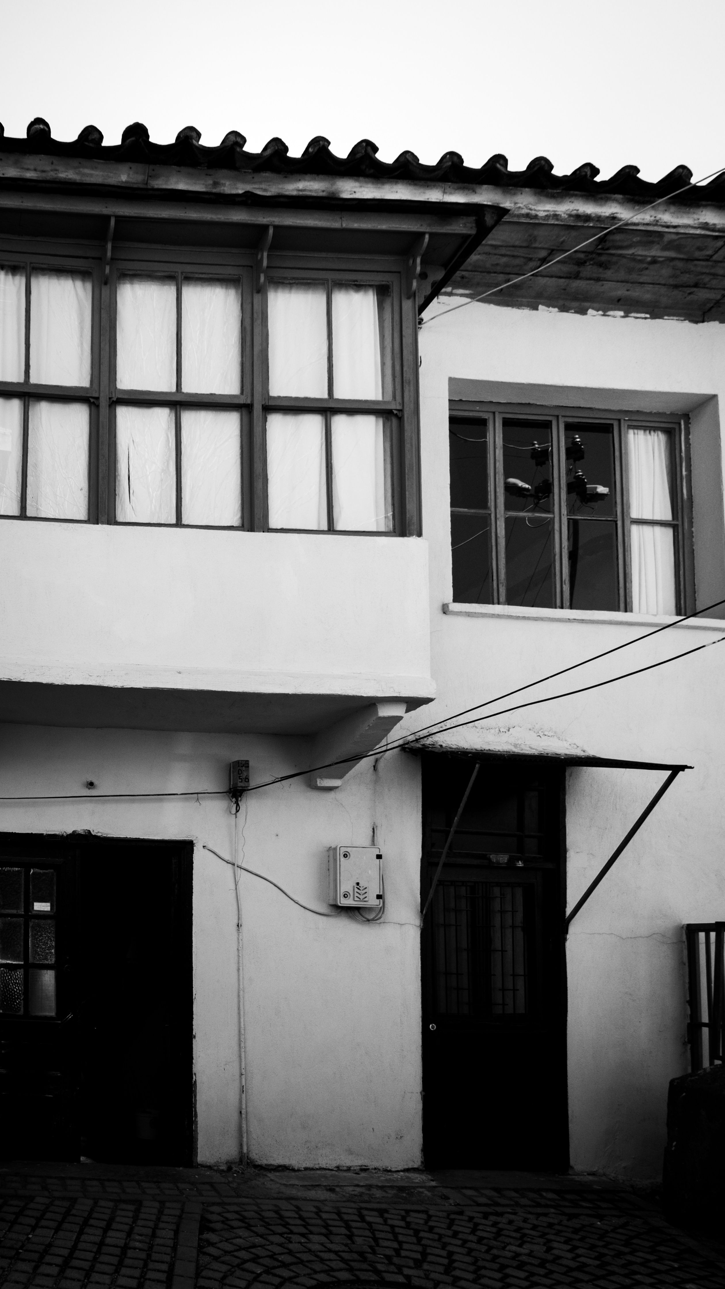 Monochrome view of an old residential building's facade with windows and doors.