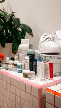 Contemporary bathroom setup featuring cosmetics, white sneakers, and green plant decor.
