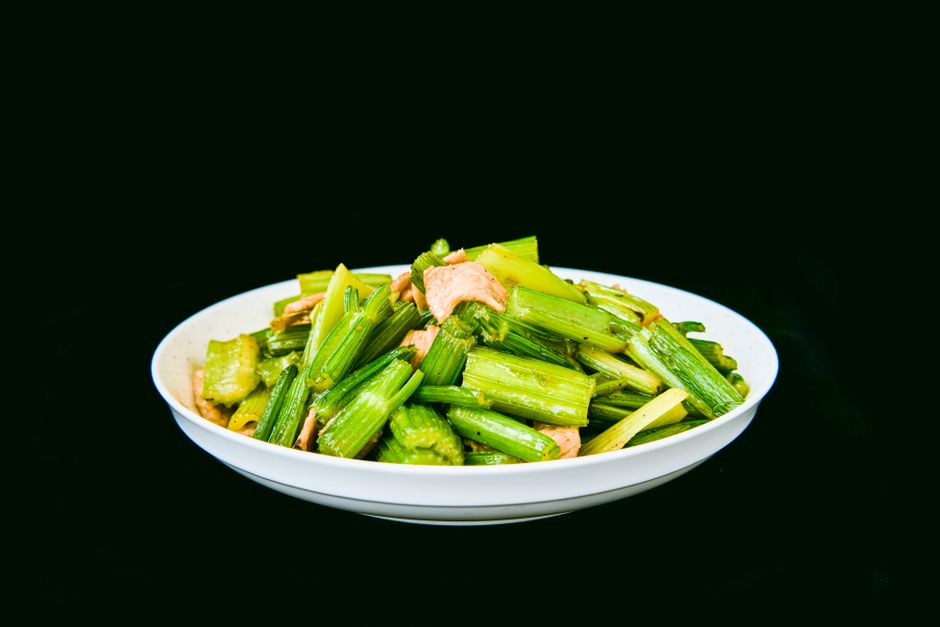 A bowl of flaked salmon salad mixed with mayonnaise, diced celery, red onion, and fresh dill, served with lemon wedges on the side.
