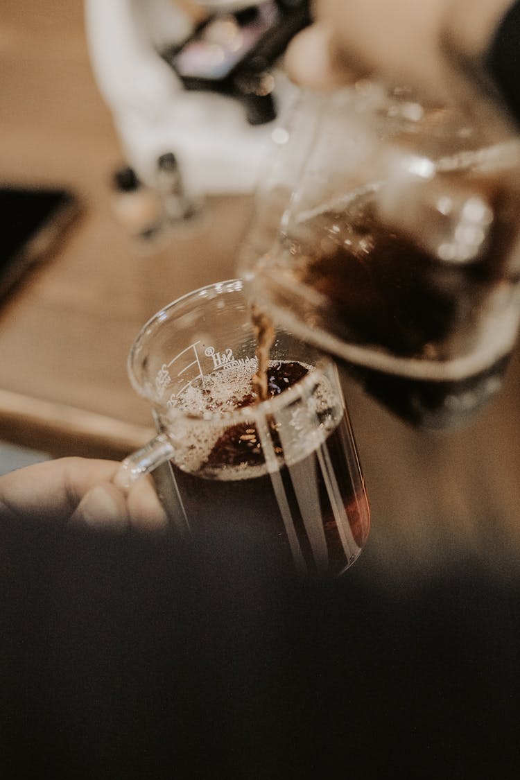 Close-up Of Man Pouring Coffee From A Pot Into A Glass