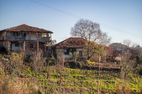 Free Crumbling houses on a hillside in rural Tirana, Albania, surrounded by trees Stock Photo