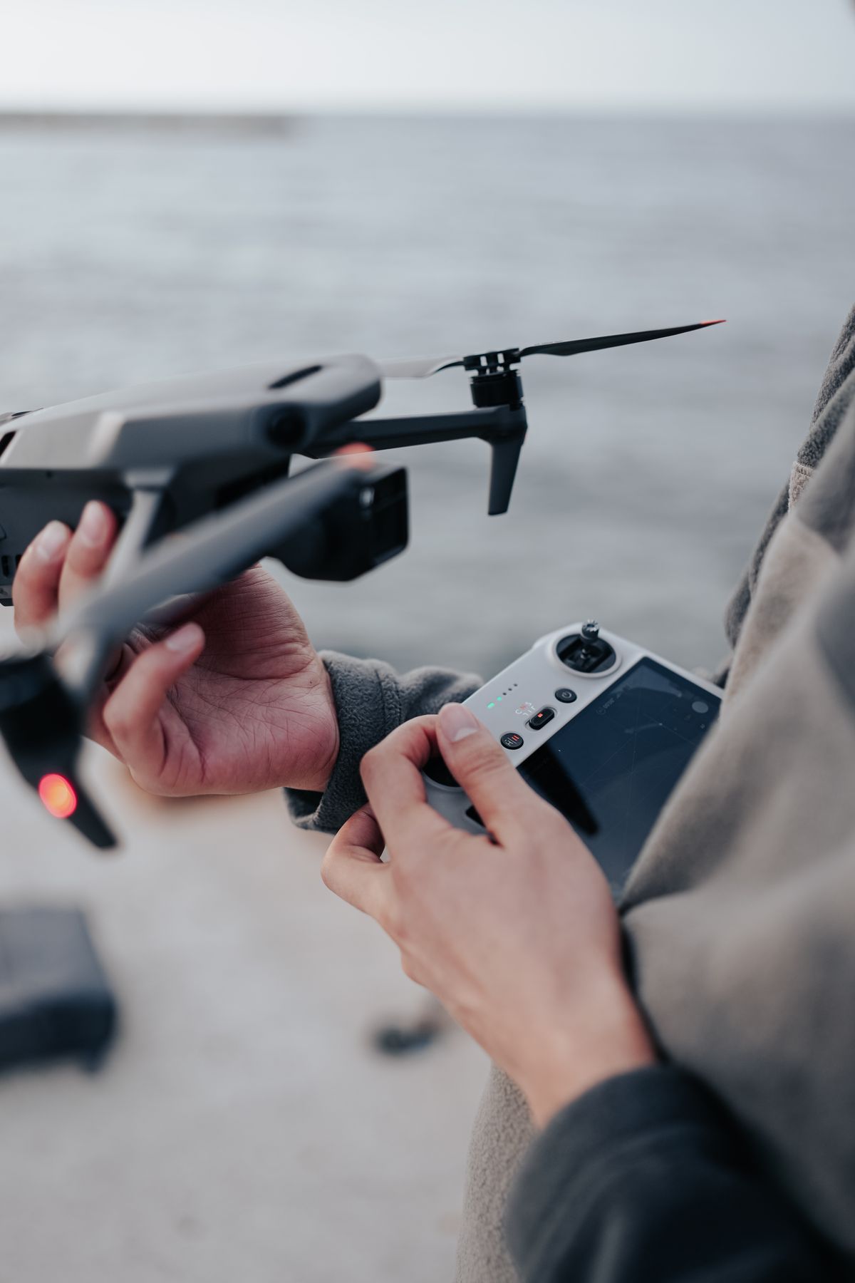 Pilot holding a drone and controller in an open field