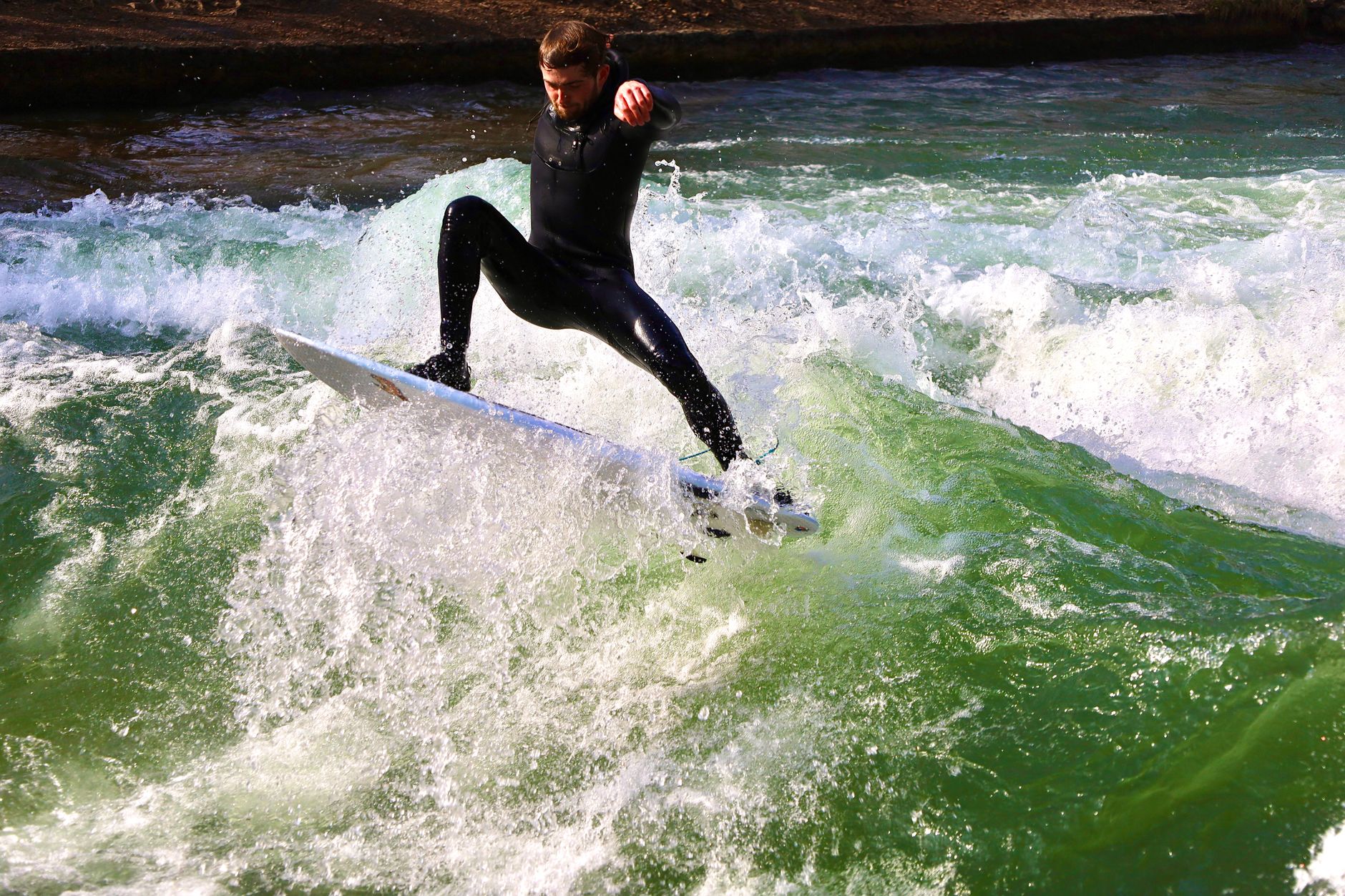 Surfer riding the Eisbachwelle standing wave in Munich Germany