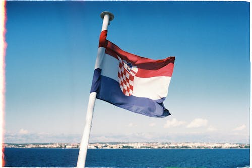 Close-up of the Flag of Croatia on the Background of the Sea and Blue Sky 