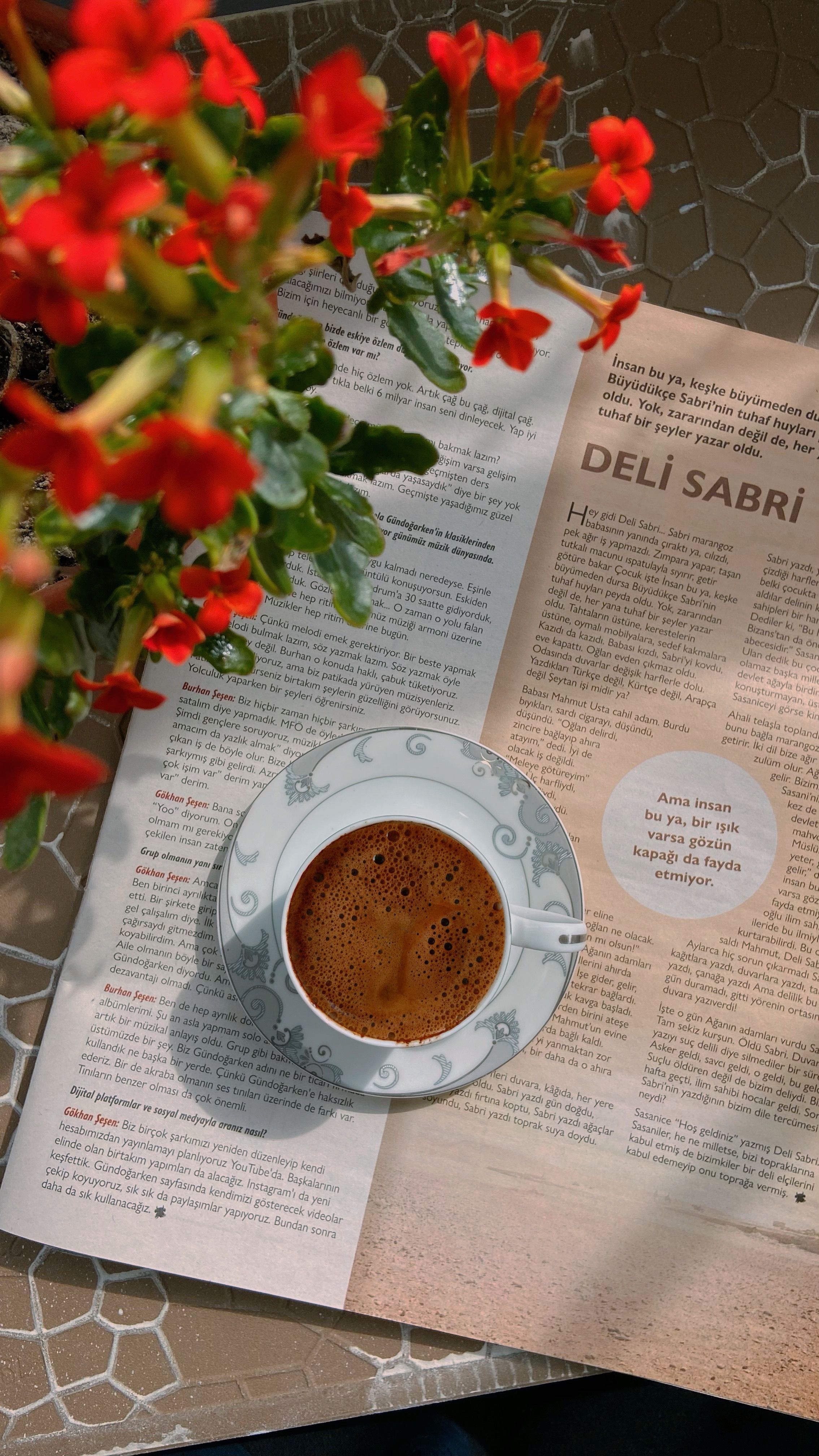 Top view of coffee cup with flowers and open magazine, creating a relaxing vibe.