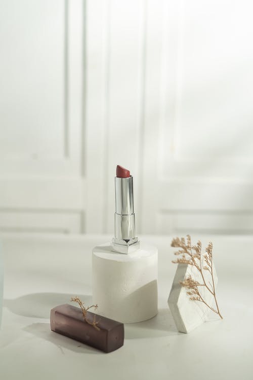 A Lipstick in a Silver Container Standing among Minimalist Decorations 