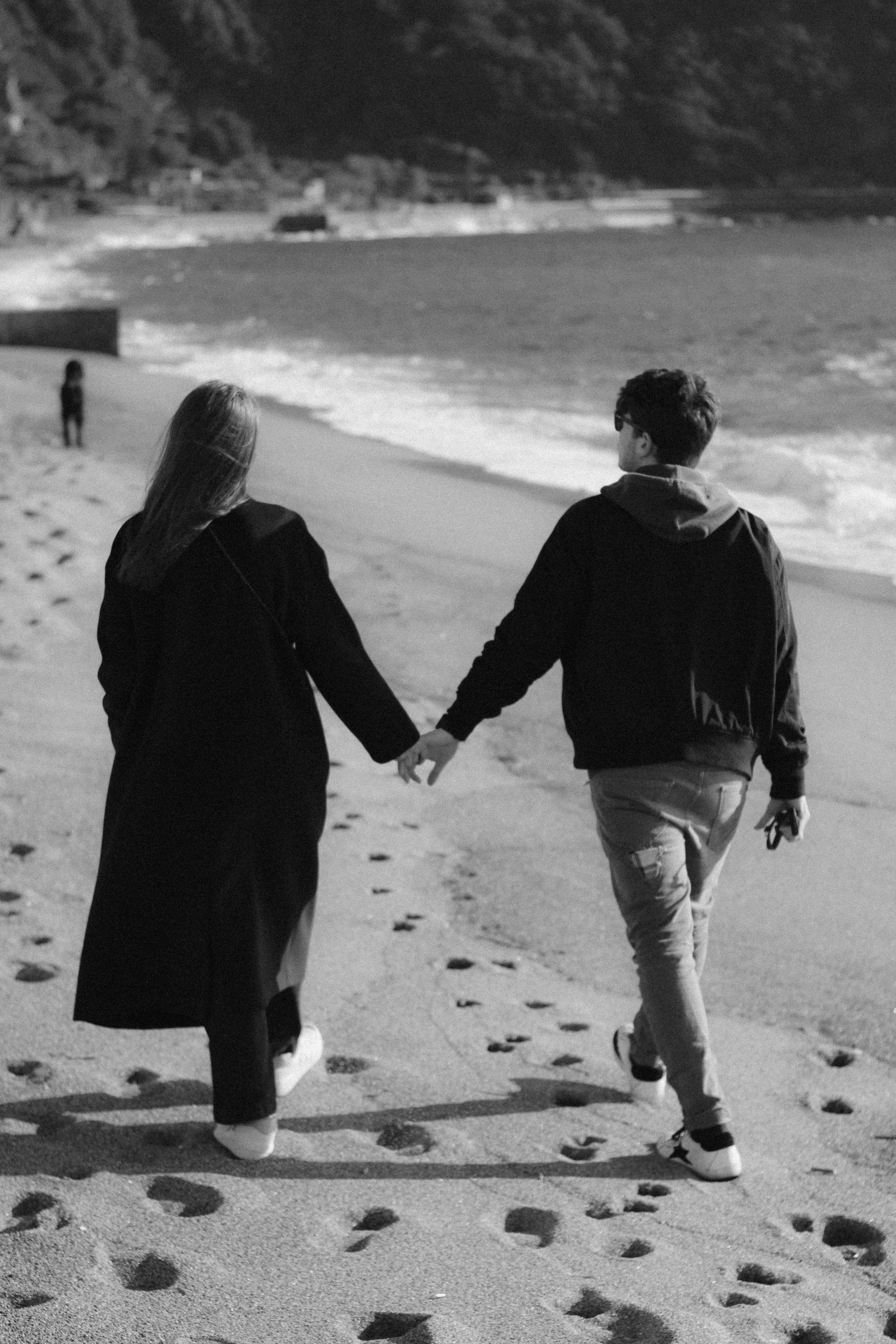 Black and White Photo of a Young Couple Walking on the Beach Holding ...