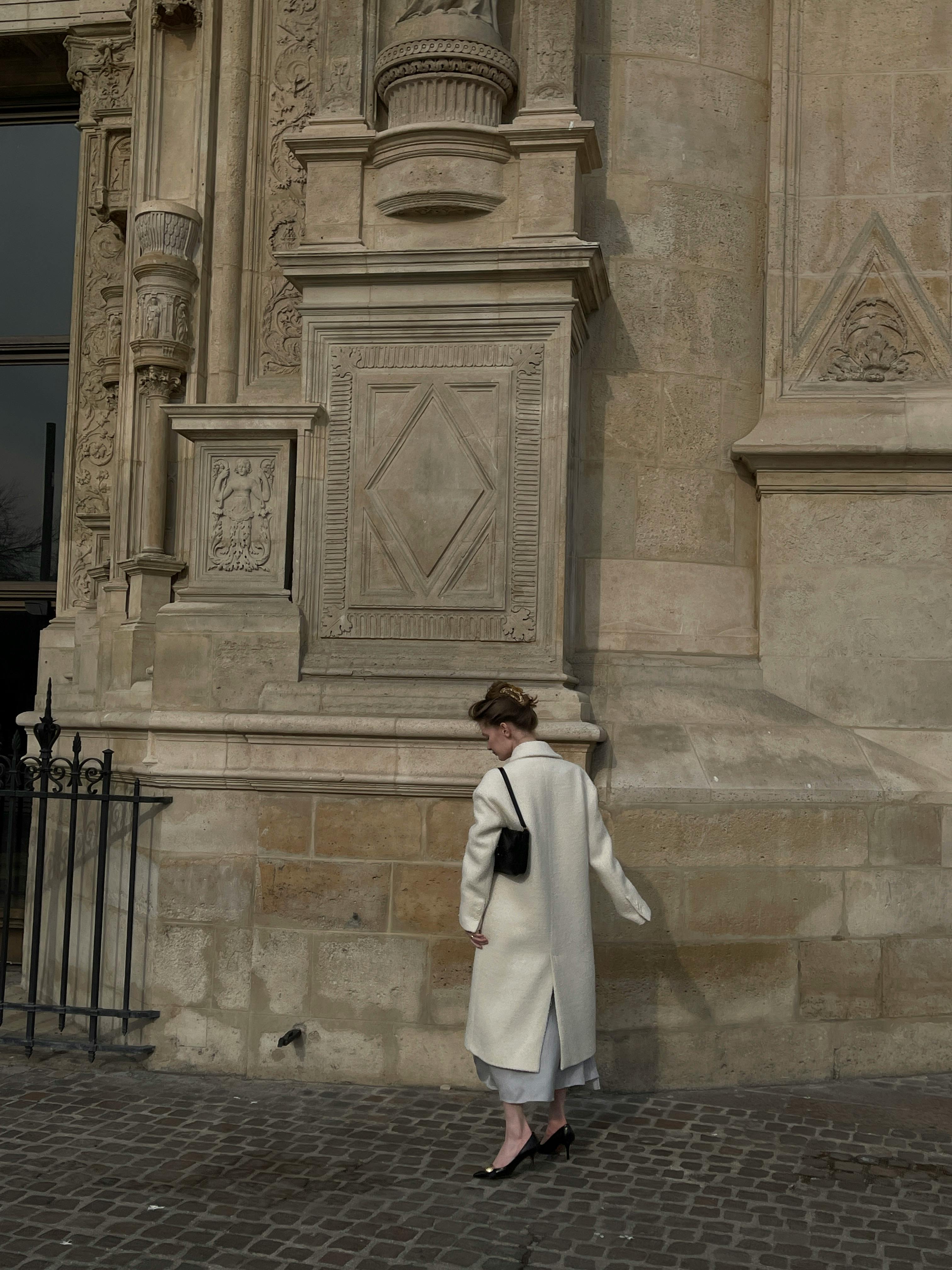 A woman elegantly walks by a historic church facade, showcasing urban fashion.