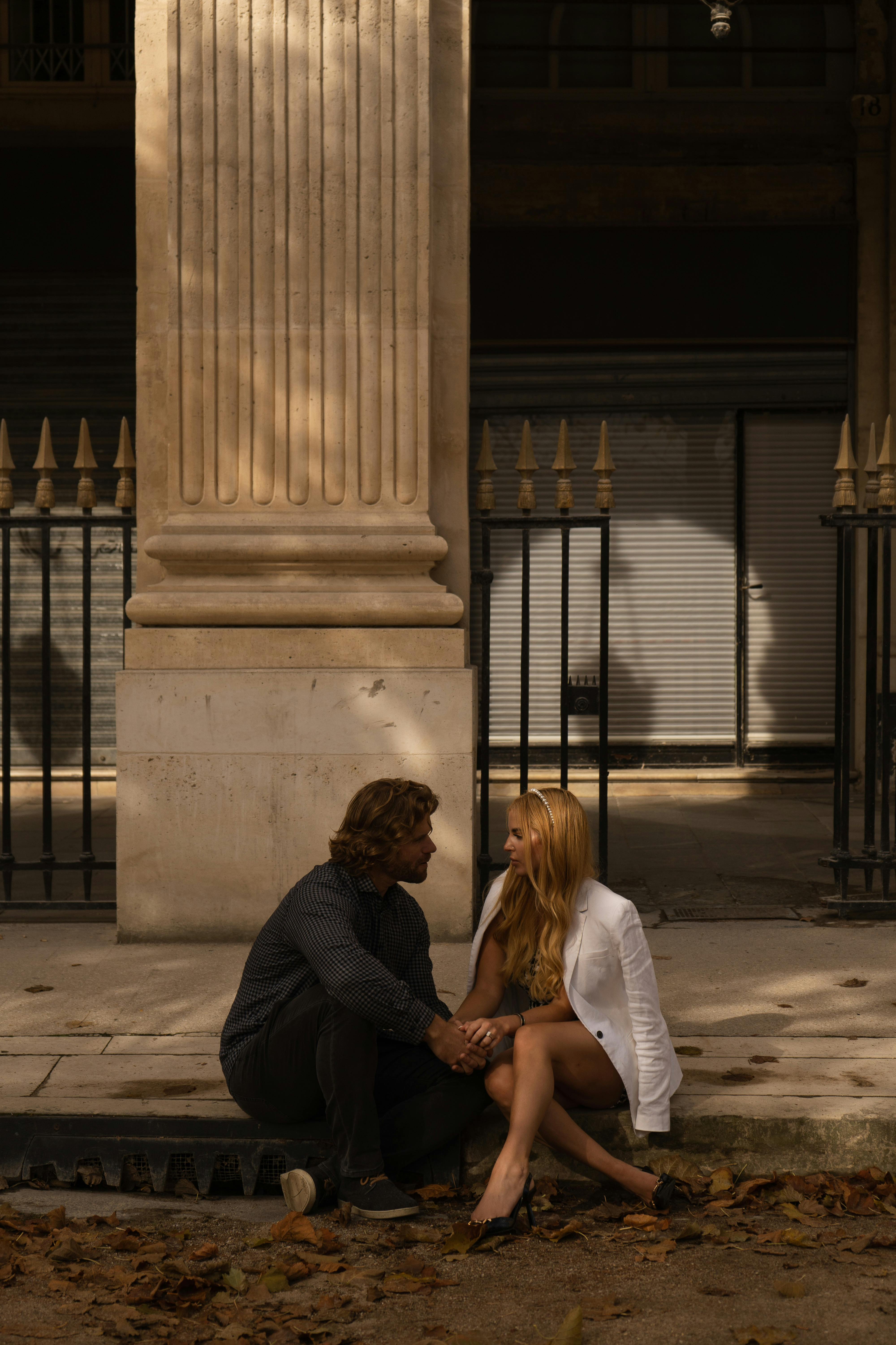 A couple seated on a city sidewalk, sharing a romantic moment in natural light.