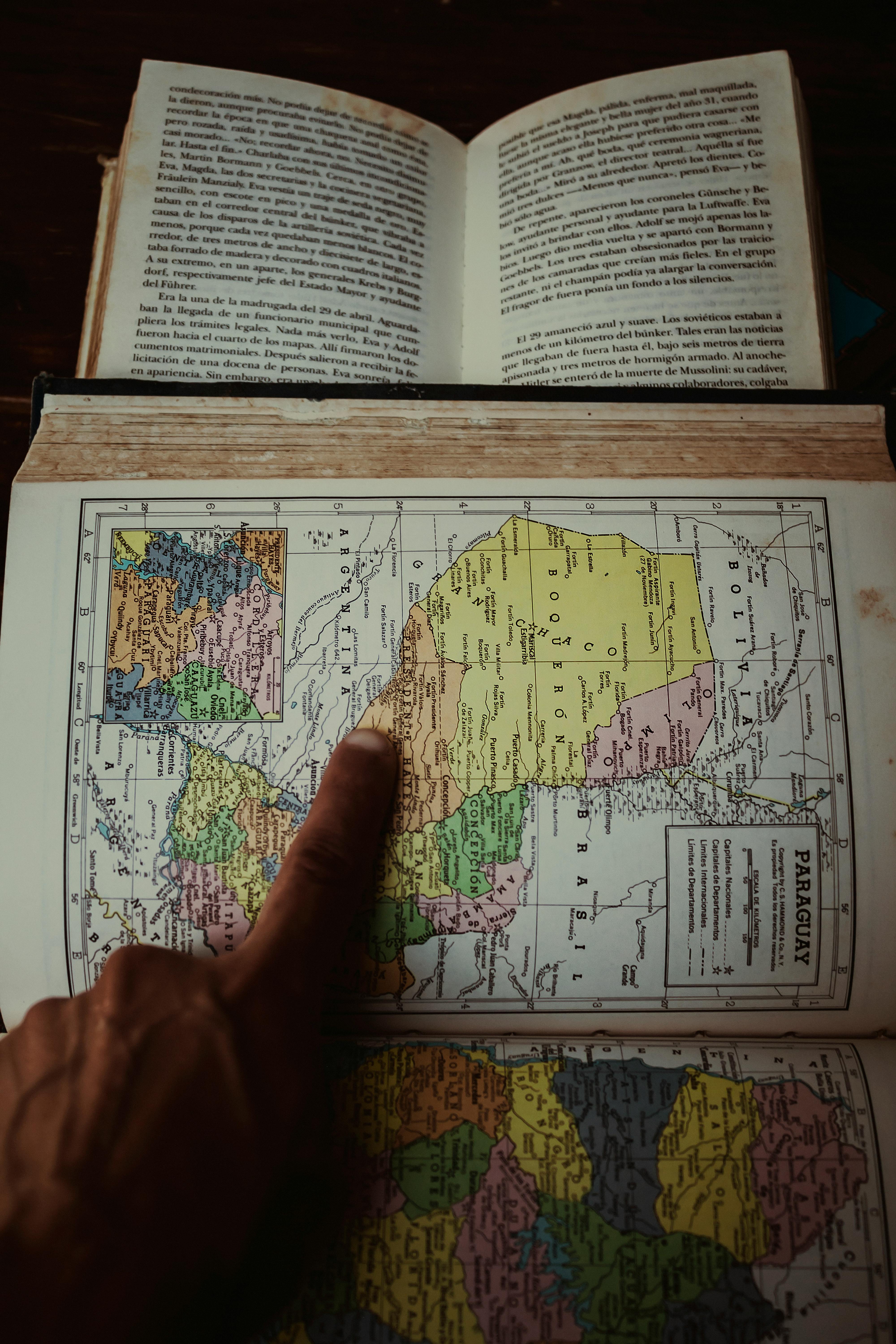 a person pointing at a map on a book