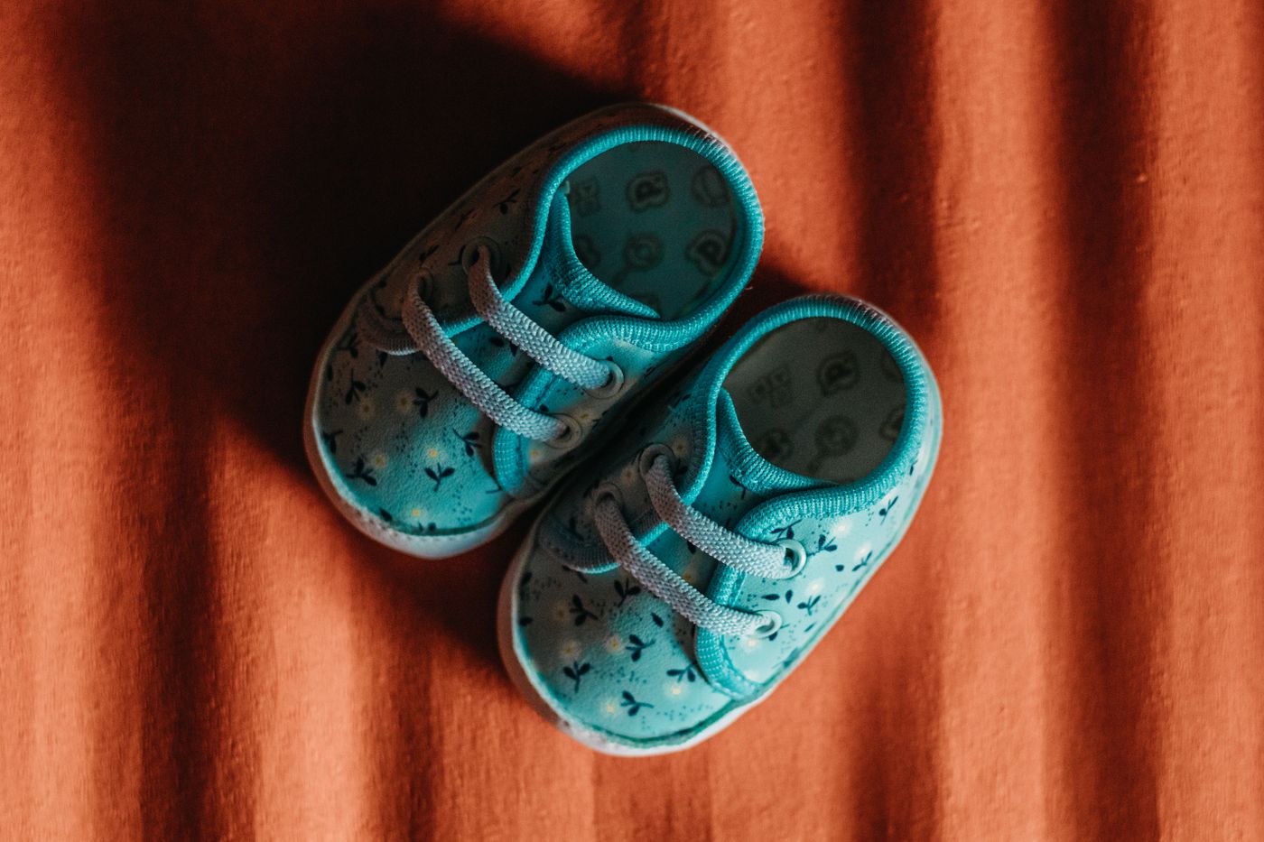 Tiny blue baby shoes resting on warm soft fabric