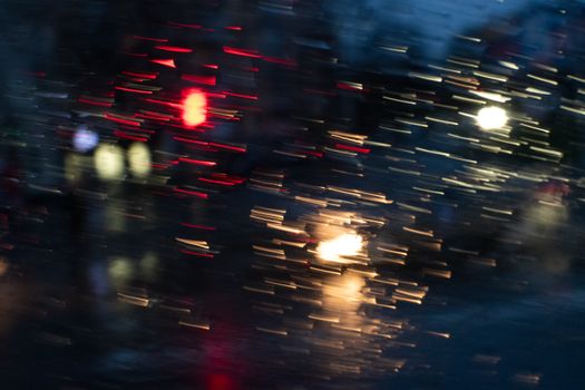 Abstract motion blur of car lights through rainy windshield at night.