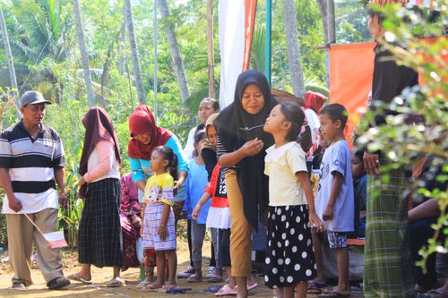 Free A lively outdoor gathering with children and adults interacting in sunlight near trees. Stock Photo
