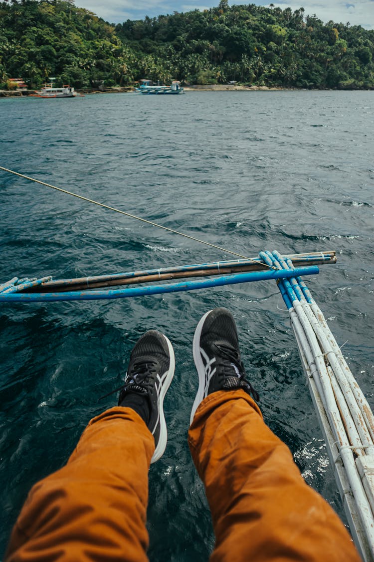 Man Sitting In A Boat With His Feet Above Water 