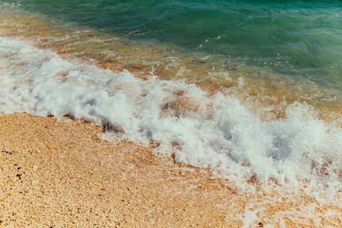 Free A tranquil beach with gentle waves lapping the sandy shore, capturing nature's beauty. Stock Photo