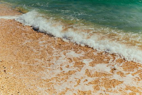 Free A serene image of waves gently splashing onto a sandy beach, capturing the essence of nature. Stock Photo