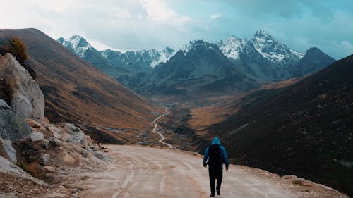 Man Hiking on Dirt Road in Mountains