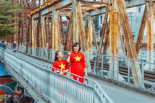 Photo of a Woman walking on a Bridge with her Daughter 