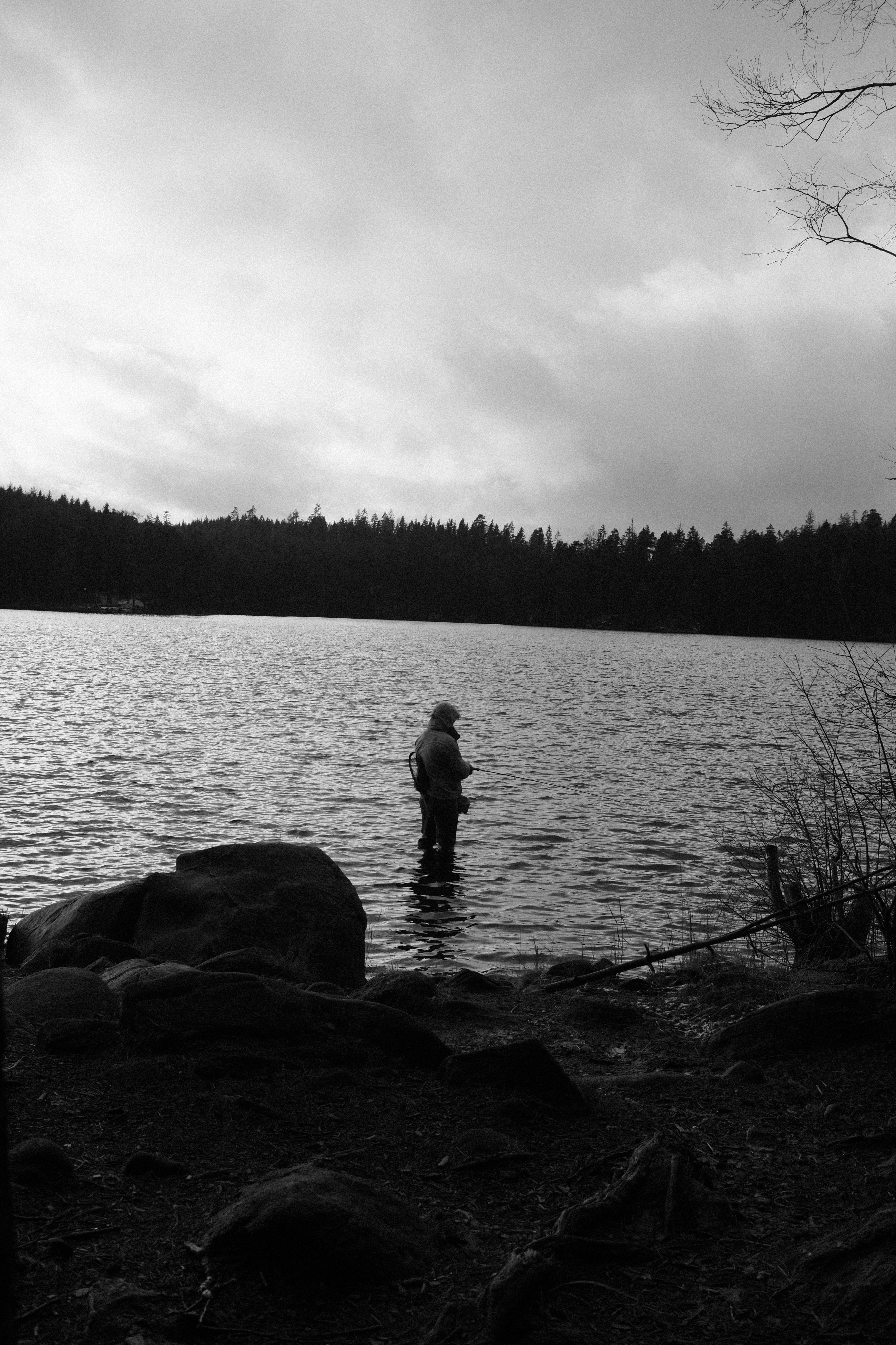 A lone figure fishes peacefully in a scenic river setting, epitomizing tranquility and leisure.