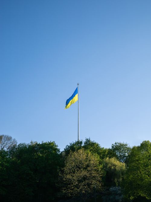 Free The Ukrainian flag waves proudly above a verdant park in Kyiv under a clear blue sky. Stock Photo
