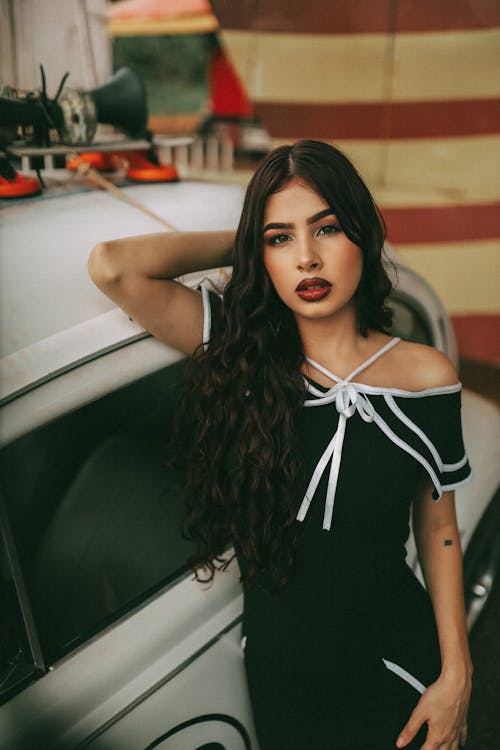 Beautiful Young Woman Leaning on a Vintage Car