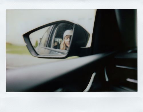 Free Close-up view of a woman's reflection in a car side mirror, showcasing travel vibes. Stock Photo