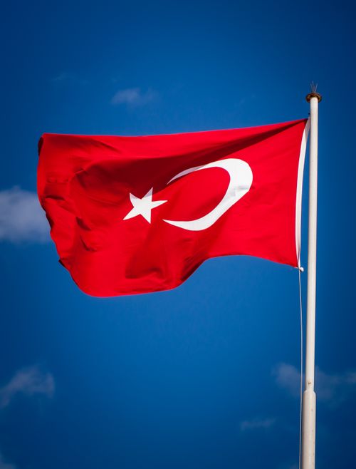 Free Vibrant Turkish flag waving against a clear blue sky in İzmir, Türkiye. Stock Photo