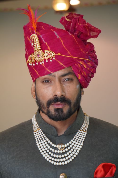 Free Portrait of a groom in a traditional Indian turban and jewelry, exuding elegance. Stock Photo