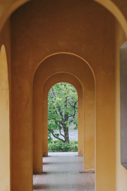 A series of architectural arches framing a lush green garden view.
