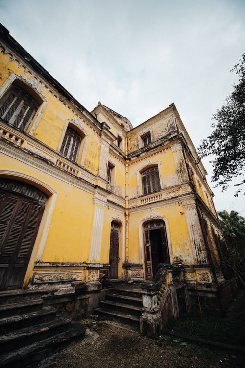 Free A weathered, abandoned yellow villa in Hue, Vietnam with rustic architecture and historical charm. Stock Photo