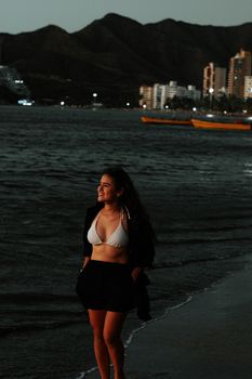 Woman enjoying a peaceful walk along Santa Marta beach during sunset in Colombia.