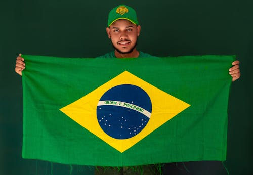 Photo of a Man Holding a Brazilian Flag