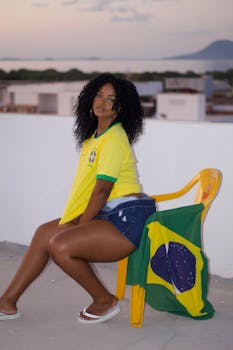 A woman sitting outdoors with a Brazilian flag, showcasing national pride and support.