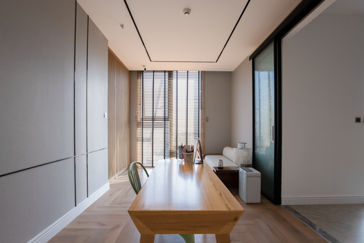 A spacious and bright dining room featuring minimalist decor, a wooden table, and natural light.