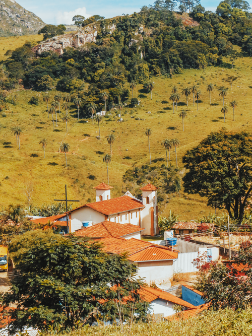 Free Picturesque rural village with a traditional church, nestled among lush mountains and trees. Stock Photo