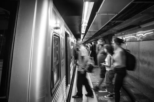 Black and White Photo of People Boarding an Underground Train